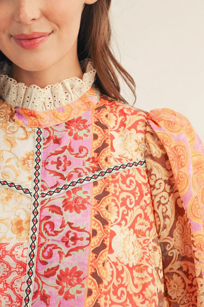 lightweight blouse with a colorful mixed print design in shades of orange, red, pink, and yellow
