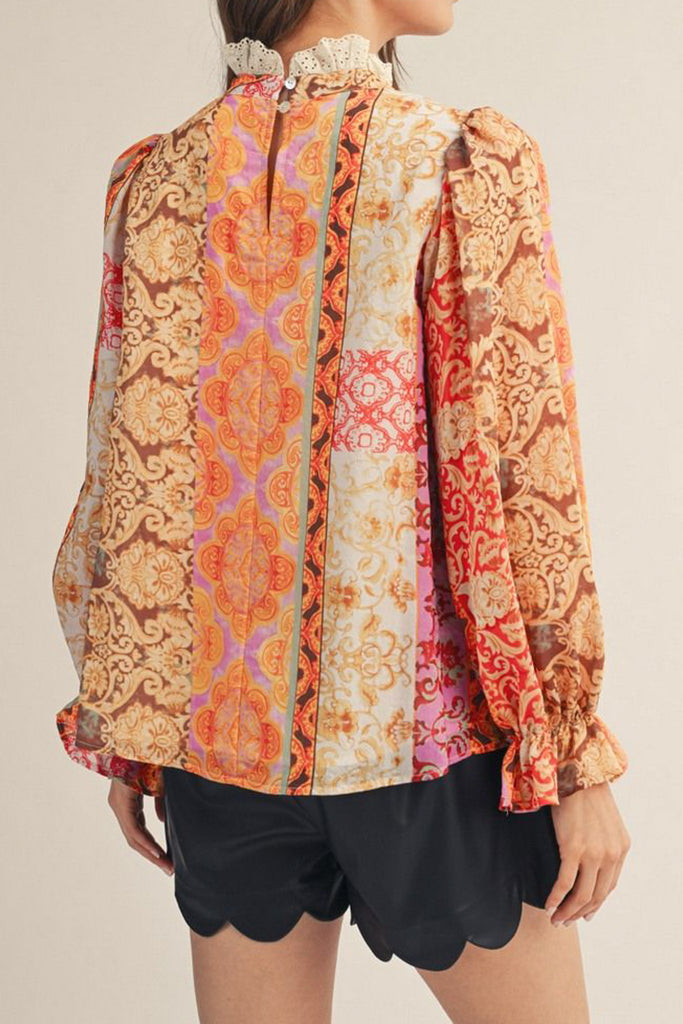 lightweight blouse with a colorful mixed print design in shades of orange, red, pink, and yellow