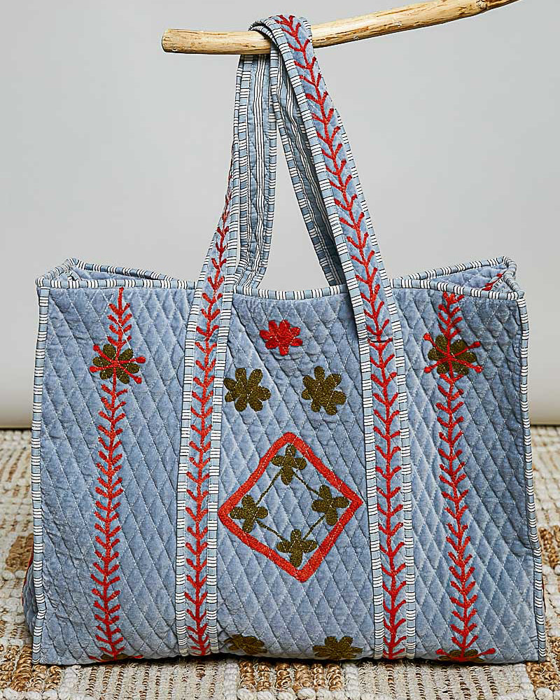 oversized quilted tote bag in faded denim blue with embroidered details in red and green