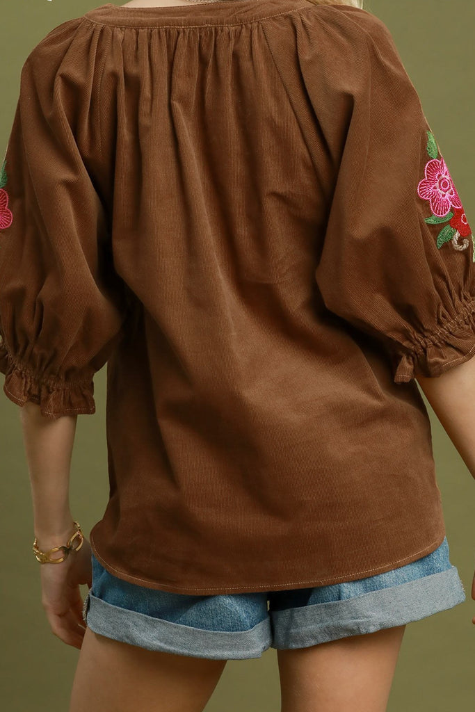 camel brown corduroy top with colorful embroidered floral details on sleeves.