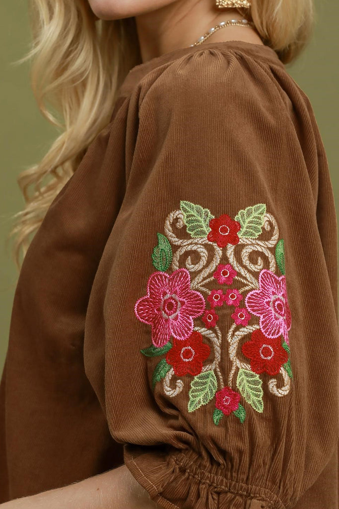 camel brown corduroy top with colorful embroidered floral details on sleeves.