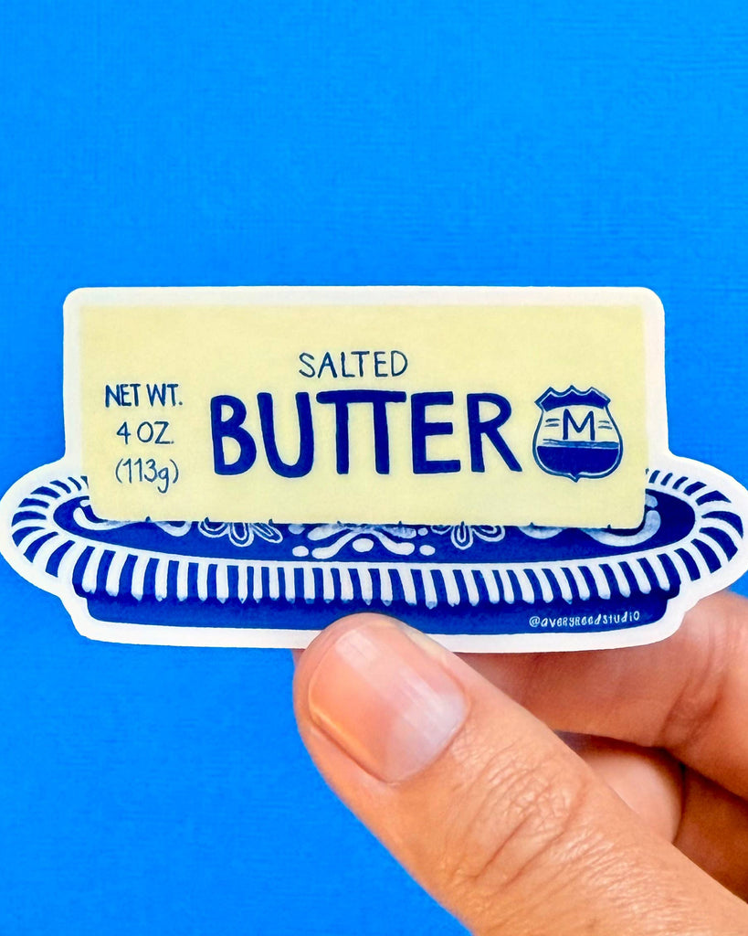 die-cut sticker in the shape of a stick of butter on a blue and white china dish