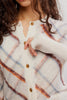 free people fitted white cardigan with a muted plaid design.
