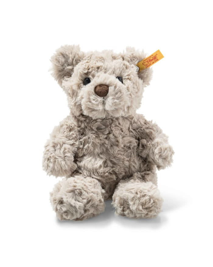 A small plush teddy bear in light taupe-gray curly fur, sitting against a plain white background. It has a small orange-yellow Steiff ear tag on its right ear.