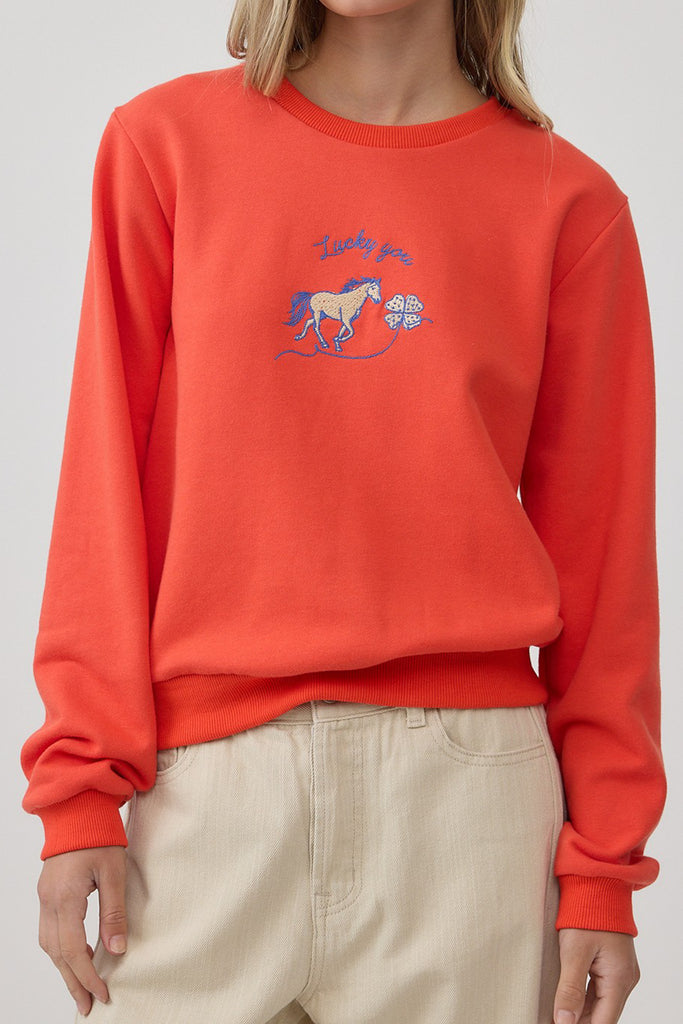 orange crew neck sweatshirt with an embroidered horse design and the message "lucky you."
