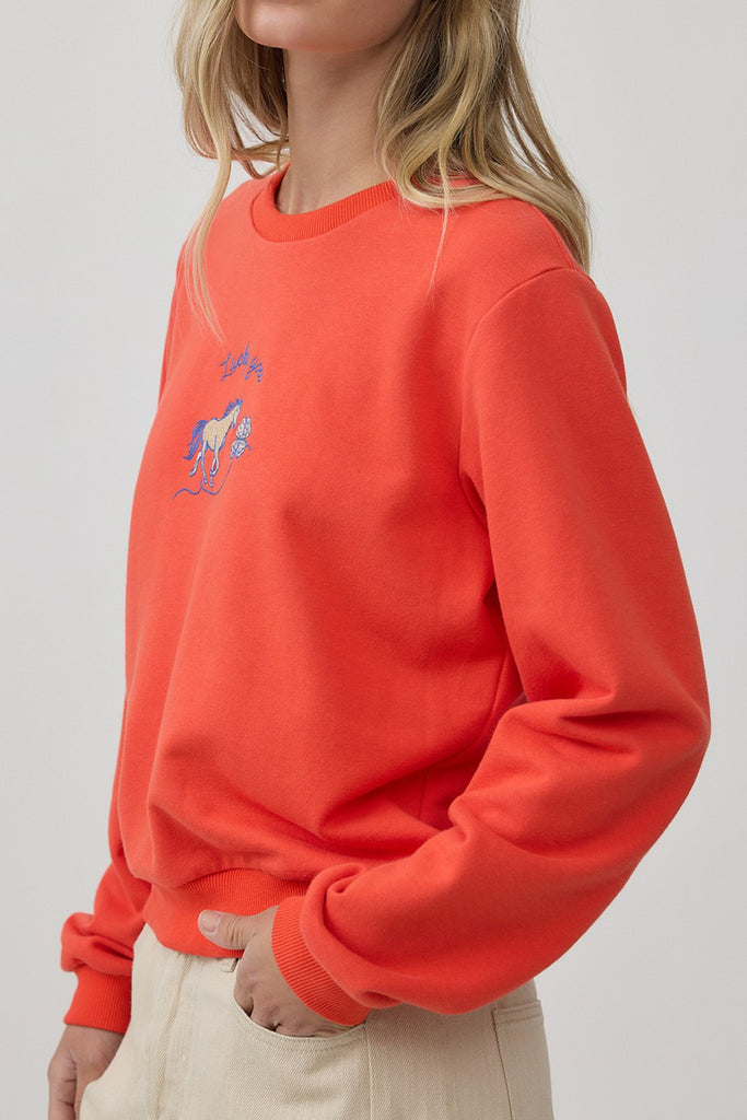orange crew neck sweatshirt with an embroidered horse design and the message "lucky you."