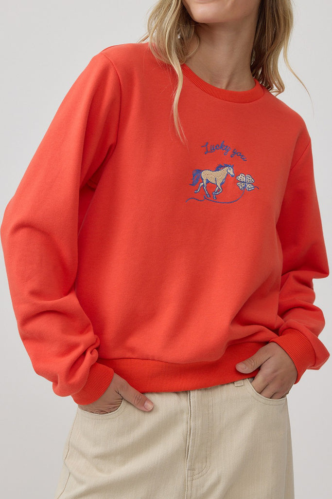orange crew neck sweatshirt with an embroidered horse design and the message "lucky you."