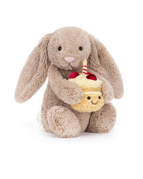 bashful beige birthday bunny, plush beige bunny holding a smiling birthday cake topped with strawberries and a candle
