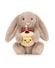 bashful beige birthday bunny, plush beige bunny holding a smiling birthday cake topped with strawberries and a candle