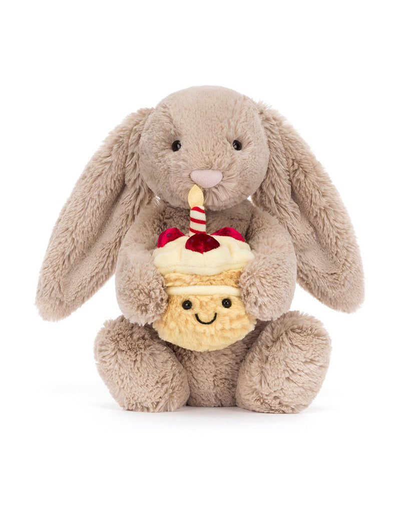 bashful beige birthday bunny, plush beige bunny holding a smiling birthday cake topped with strawberries and a candle