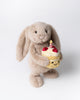 bashful beige birthday bunny, plush beige bunny holding a smiling birthday cake topped with strawberries and a candle