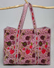 oversized quilted tote bag in a purple floral pattern with striped details. 