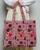 oversized quilted tote bag in a purple floral pattern with striped details. 