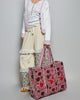 oversized quilted tote bag in a purple floral pattern with striped details. 