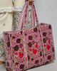 oversized quilted tote bag in a purple floral pattern with striped details. 