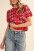 short sleeve button up sweater in red with a colorful floral pattern in cream, burgundy, and light blue.