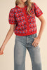 short sleeve button up sweater in red with a colorful floral pattern in cream, burgundy, and light blue.