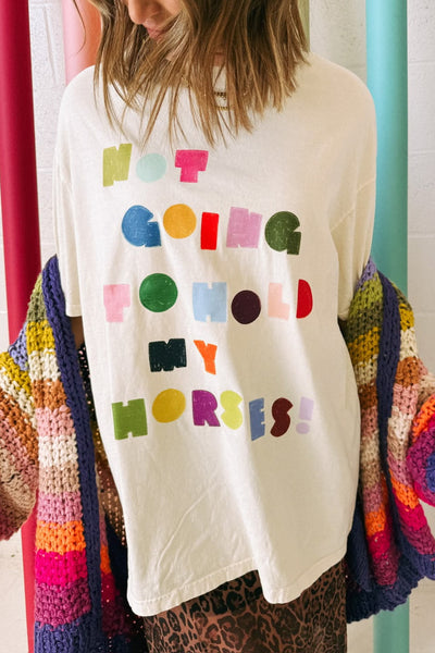 white graphic tee with the message "not going to hold my horses" in a bold and colorful design
