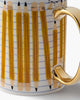 white porcelain mug with a pencil design and metallic gold detailing