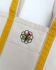 canvas tote with mustard yellow trim and colorfully embroidered personify flower logo