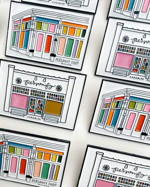 lapel pins featuring illustrations of chamblee and duluth's personify storefronts
