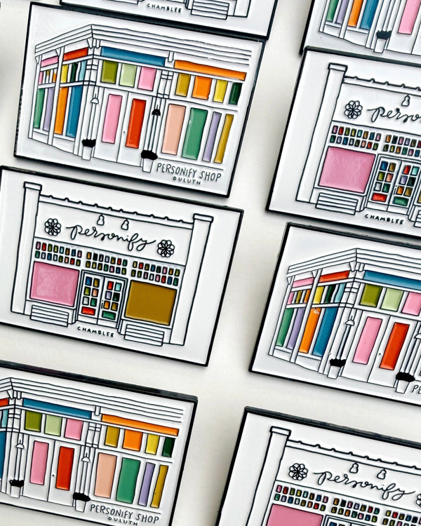 lapel pins featuring illustrations of chamblee and duluth's personify storefronts