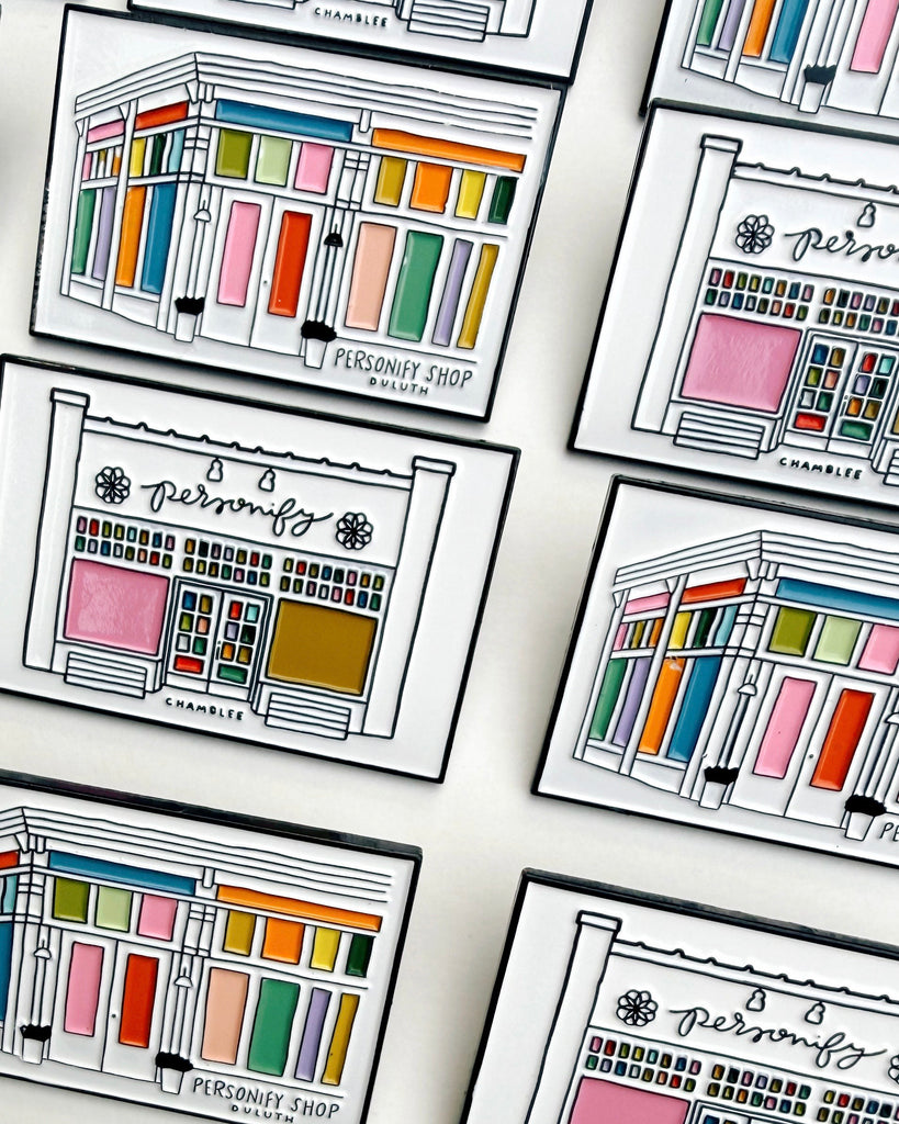 lapel pins featuring illustrations of chamblee and duluth's personify storefronts