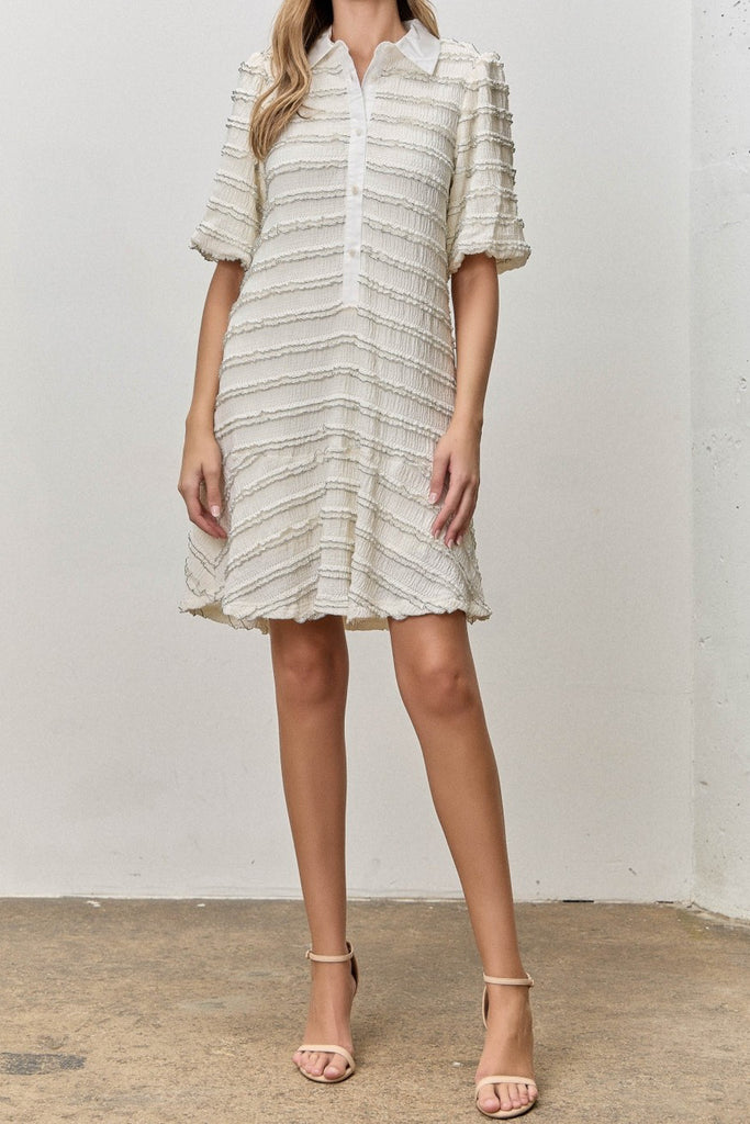 white mini dress with black trimmed ruffle details throughout