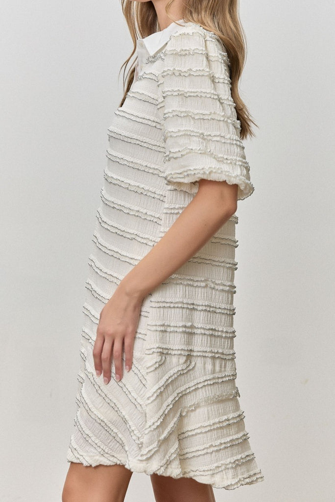 white mini dress with black trimmed ruffle details throughout