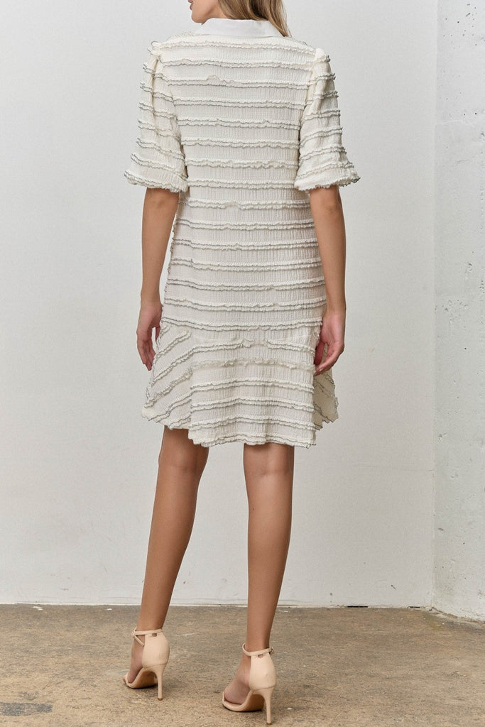 white mini dress with black trimmed ruffle details throughout