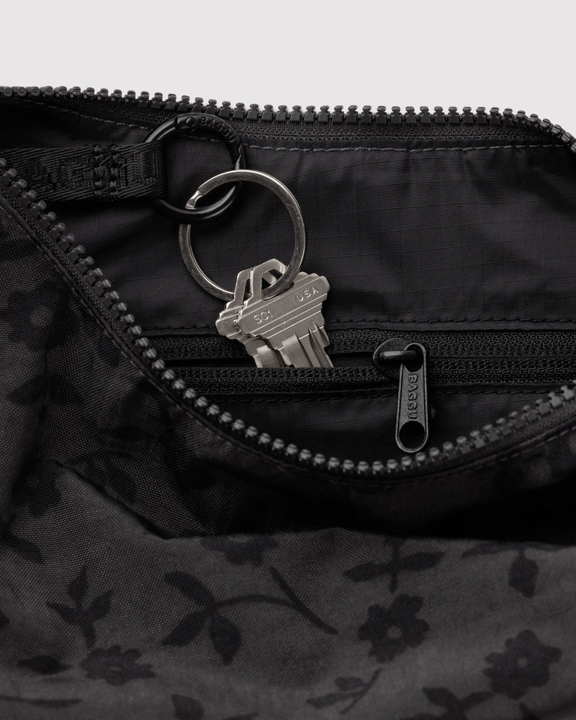small nylon crescent bag from baggu in a charcoal colored ditsy floral pattern