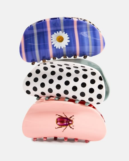 Three hair claw clips stacked vertically on a light gray background. The top clip is blue with pink stripes and a white daisy flower.