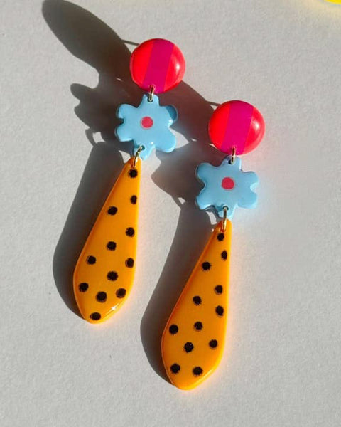 Colorful earrings with pink, blue, and orange elements on a light gray background