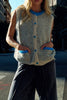 knit sweater vest in cream and light grey with bright blue detailing on buttons, neckline, and pockets