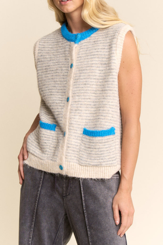 knit sweater vest in cream and light grey with bright blue detailing on buttons, neckline, and pockets