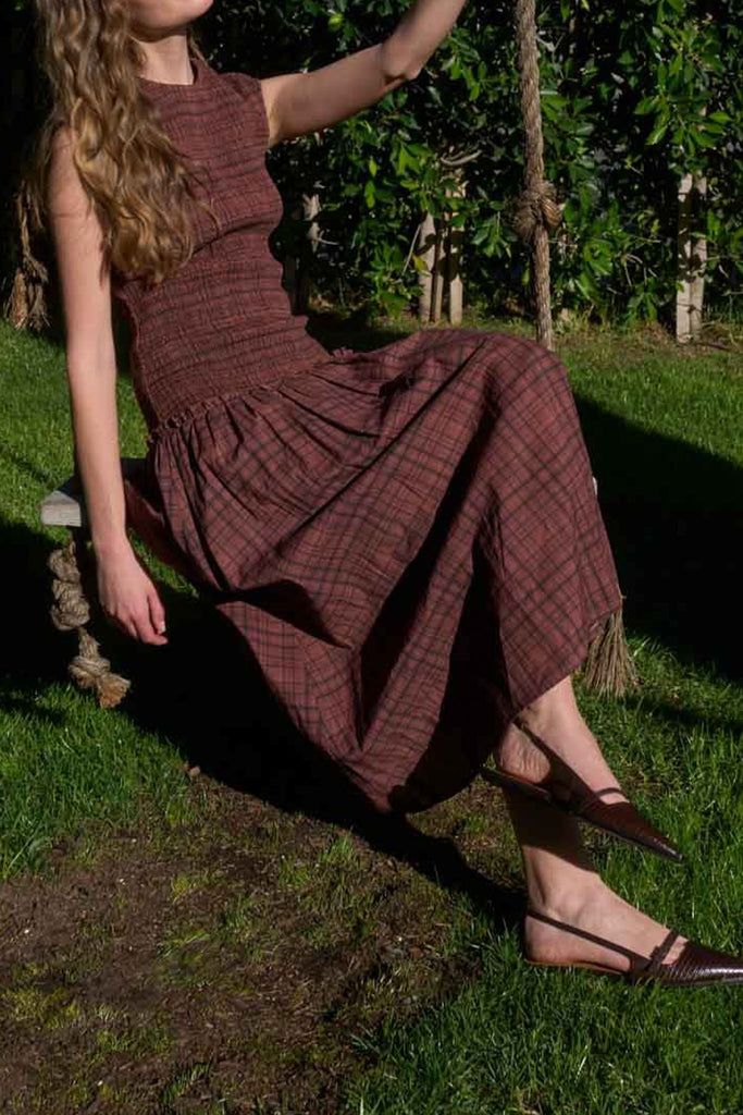 striking midi dress in a dark plaid pattern with smocked details